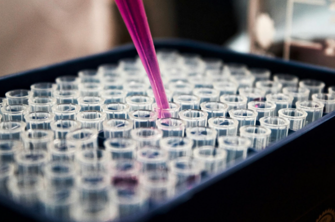 Laboratory pipette dispensing pink liquid into test tubes, symbolizing the scientific research and precision behind Botox and Dysport treatments in Santa Fe.